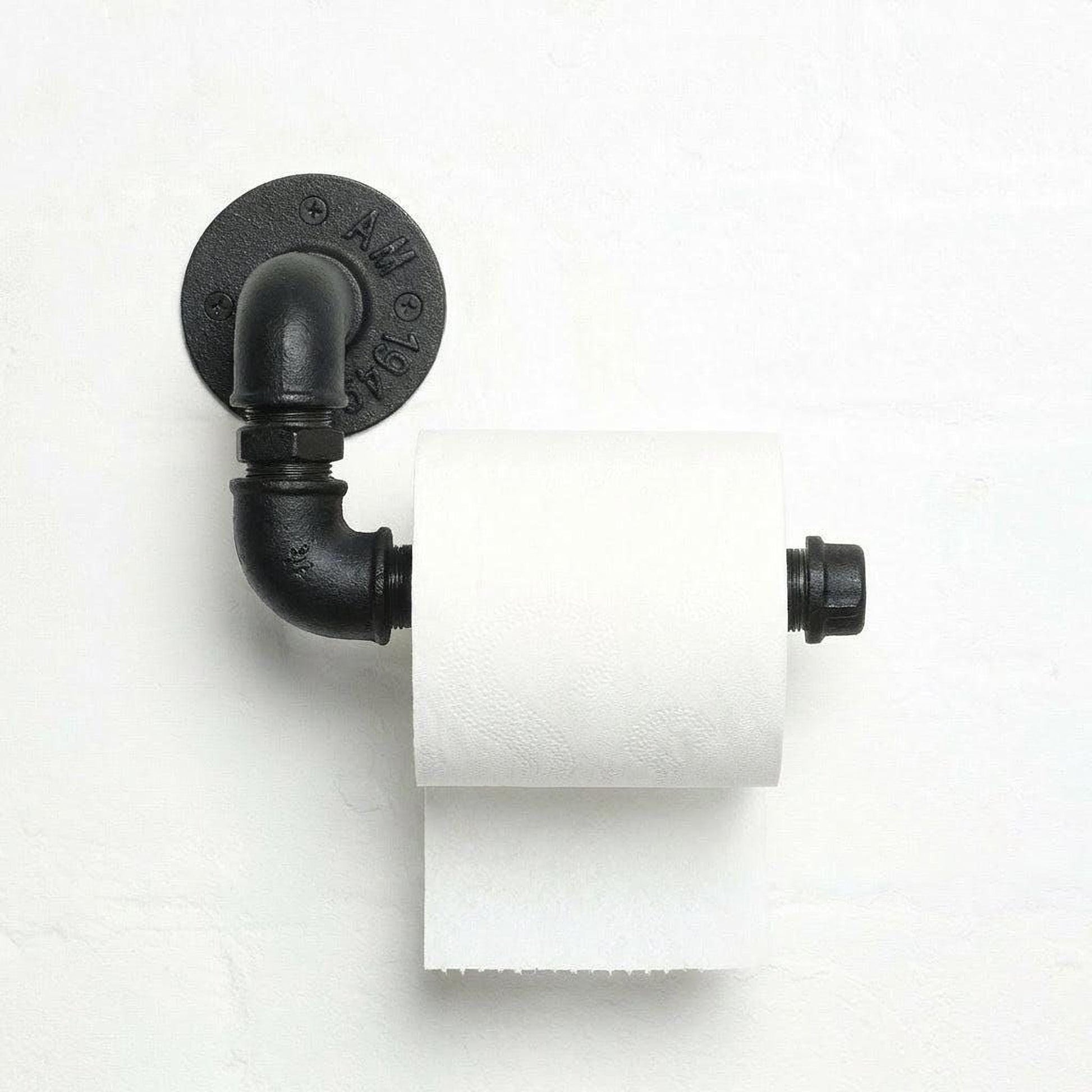 A black pipe-style toilet paper holder with a roll of white toilet paper attached to it, mounted on a white wall.
