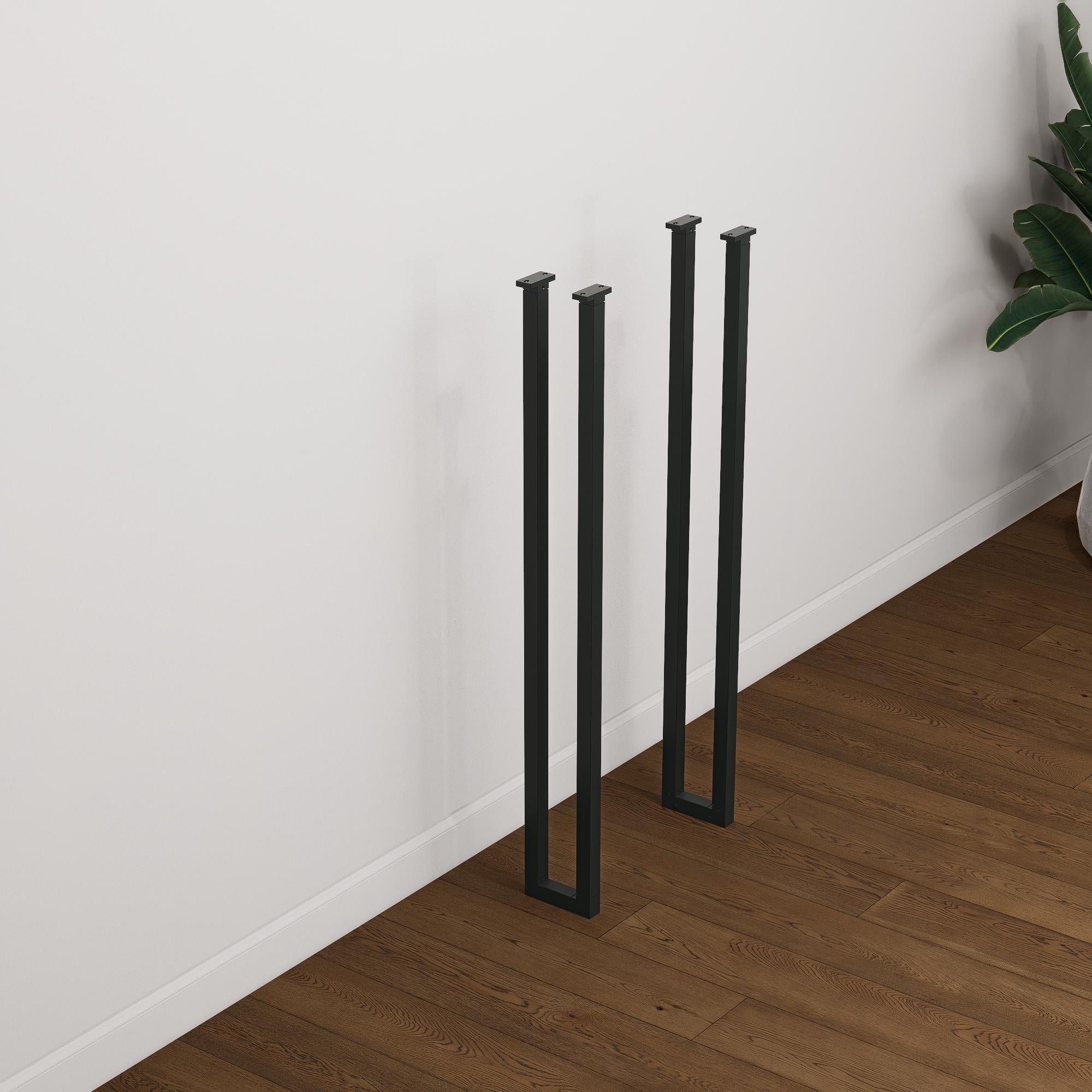 Set of two tall black industrial steel box frame table legs designed for breakfast bars or console tables, standing on wood flooring.