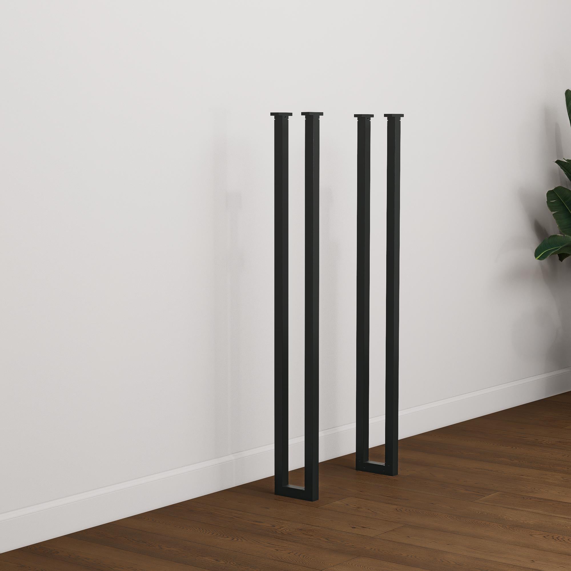 Set of two tall black industrial steel box frame table legs designed for breakfast bars or console tables, standing on wood flooring.